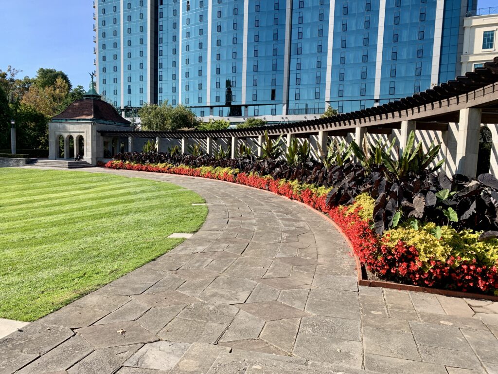 The Oaks garden displays bright flower beds with the glass facade of the Sheraton in behind. 