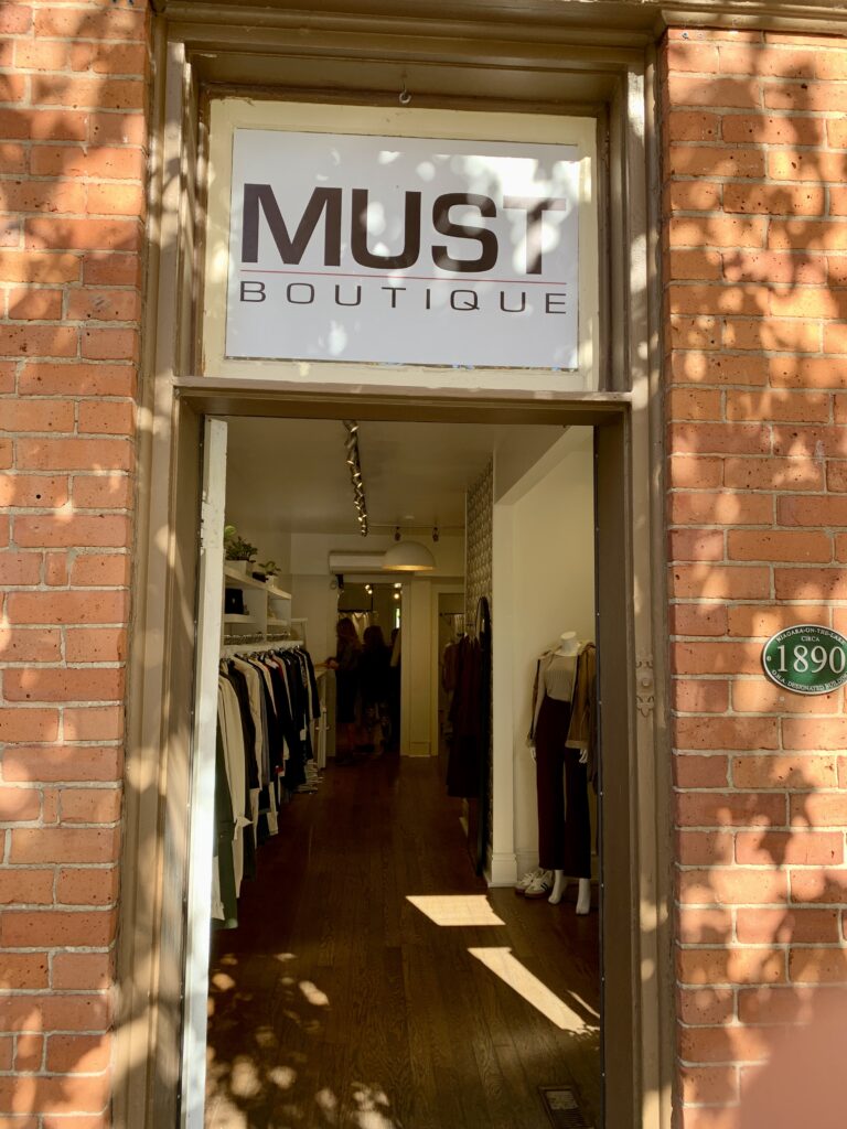 The front door to MUST boutique with the sign above the door.