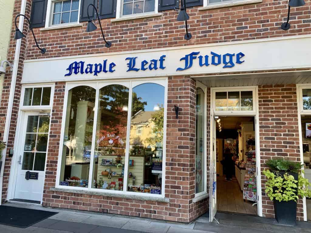 The Maple Leaf Fudge storefront is red brick with a white sign and blue gothic letters.