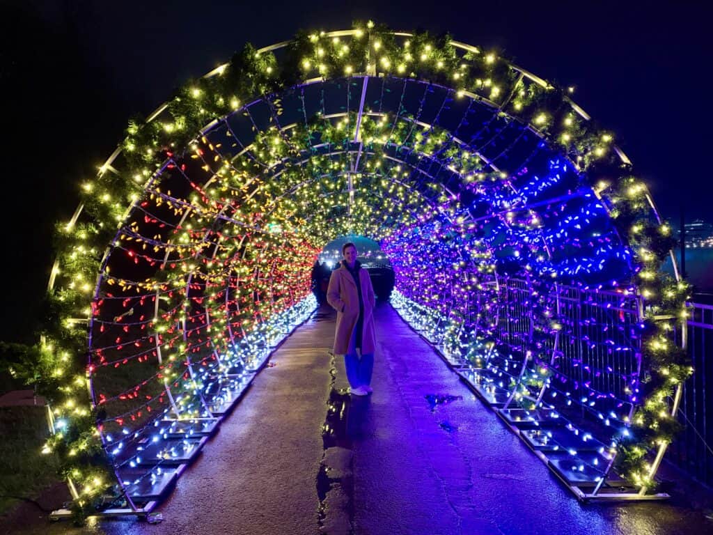 Pamela standing in a tunnel of Christmas lights