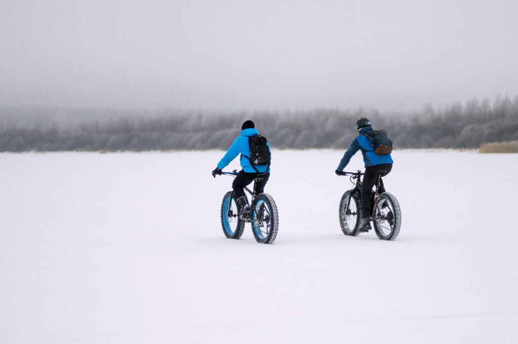 Two people fat biking through snow