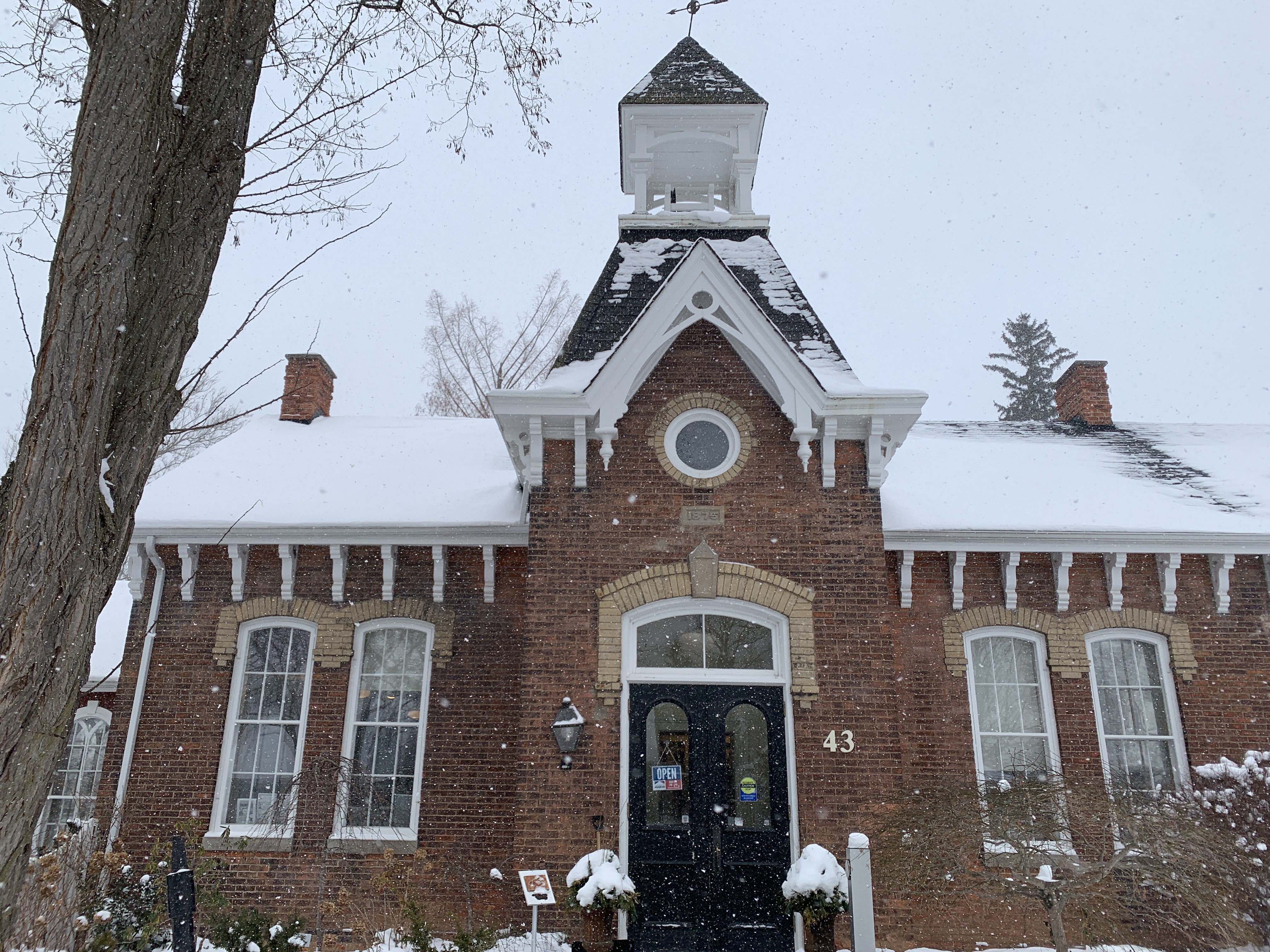 The Niagara-on-the-Lake Museum, a charming red-brick building with snow-covered roofs, surrounded by a wintry landscape. Snowfall adds a touch of seasonal beauty to this historic location.